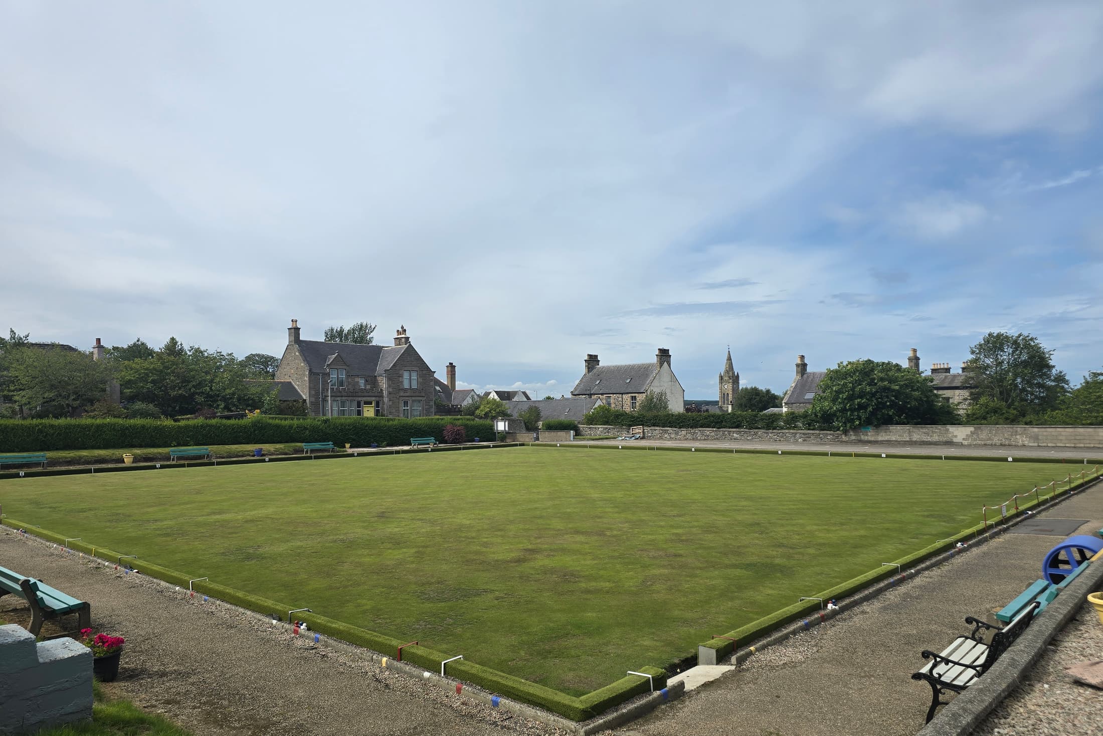 The bowling green at Cullen Bowling Club on a summer day, with the town and church spire behind