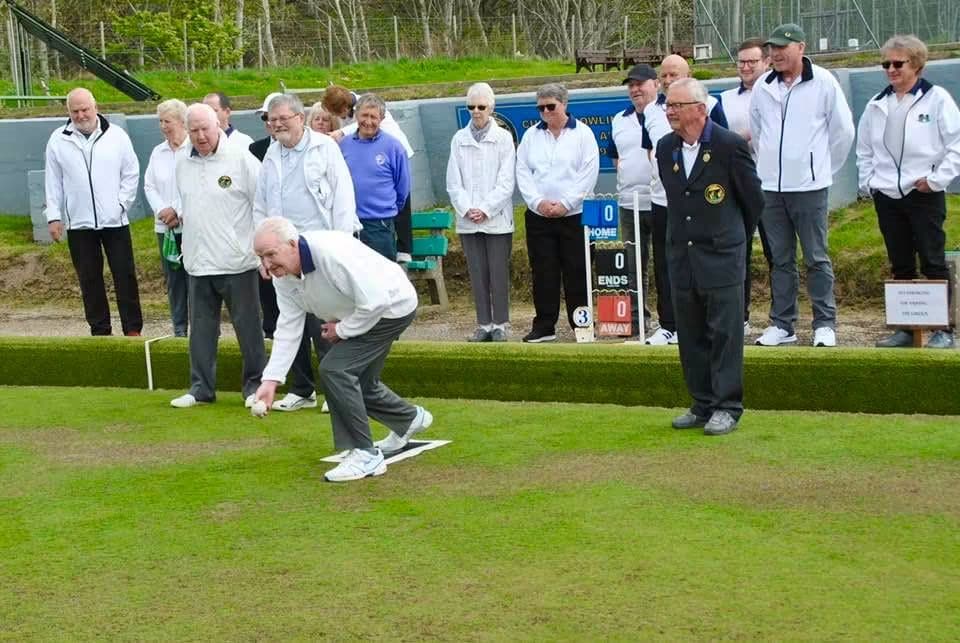 A member delivering a bowl watched by the club